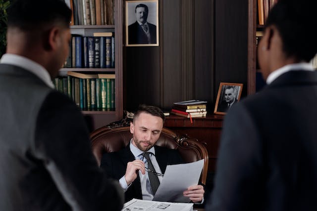 A person in a suit sitting in a chair with a person in a suit