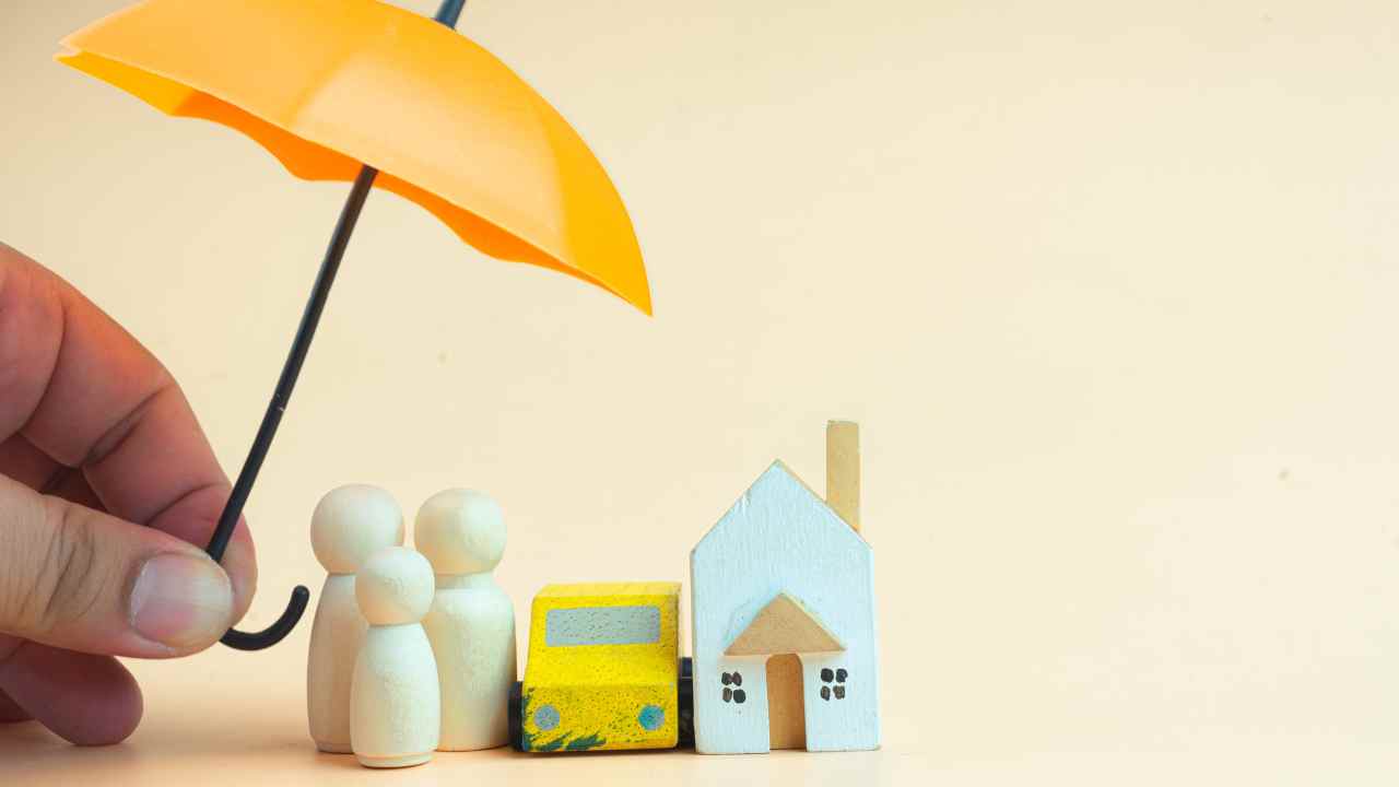 a-small-umbrella-over-figurines-of-a-family-car-and-home