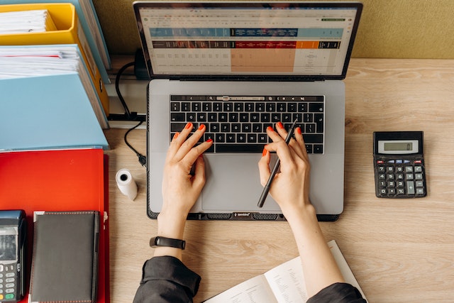 person-working-on-computer-with-calculator-next-to-them