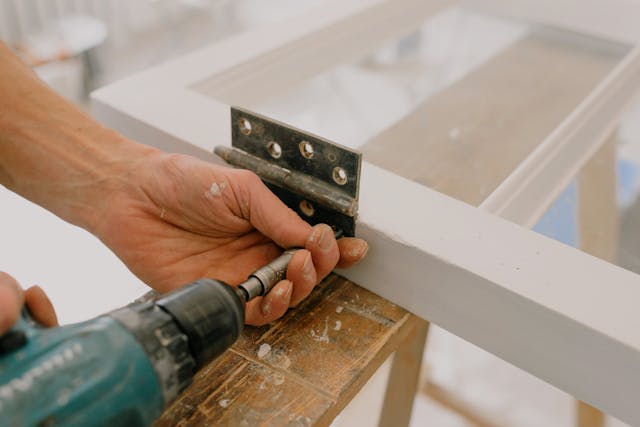 person drilling into the side of a glass door